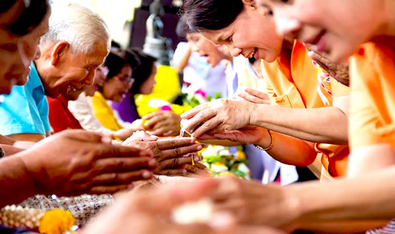 Traditional Thai Rod Nam Dam Hua ceremony during Songkran, pouring scented jasmine water on elderly hands as a gesture of gratitude and respect.