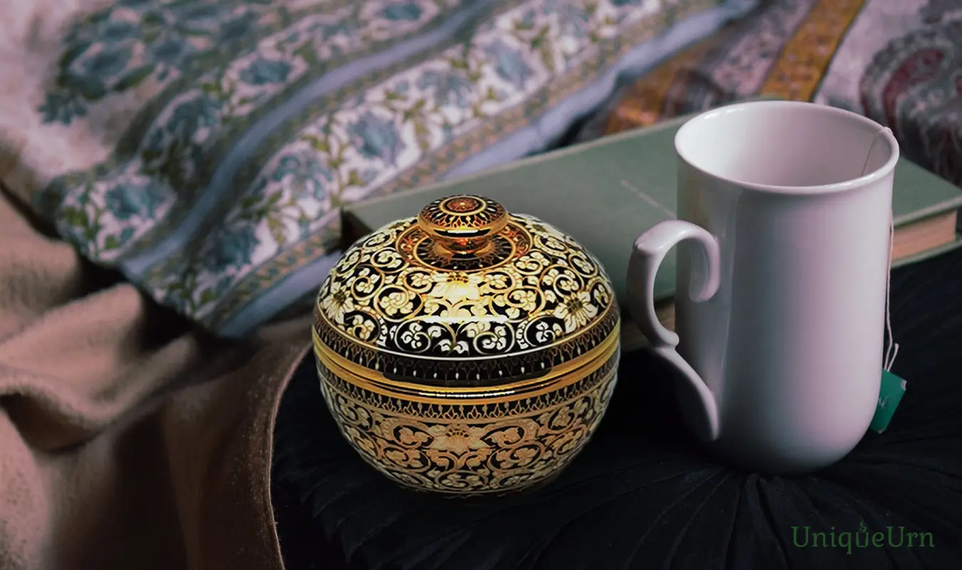 Awaken from the fear of impermanence with a hand-painted Bencharong art keepsake urn by UniqueUrn, placed next to a white mug.