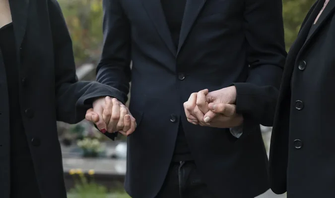 Relatives are holding hands to encourage each other to get through the moment of losing a loved one together.