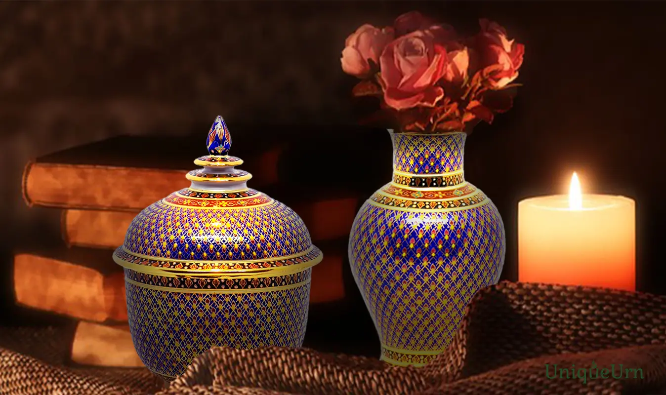A master artisan's hand-painted geometry, Kaolarmtad blue design on a porcelain Bencharong vase & Thochan keepsake urn for ashes sit on a table in the dimly lit room.